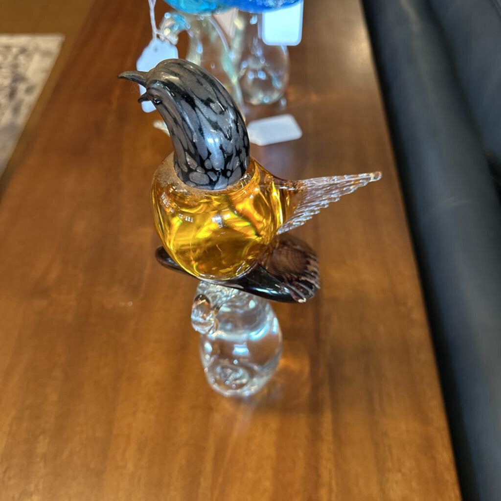 Glass bottle with a bird-shaped stopper on a wooden surface