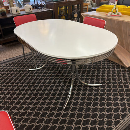 Modern dining table with a white top and chrome base on a patterned rug.