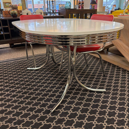 Diner-style table with red chairs on a patterned carpet