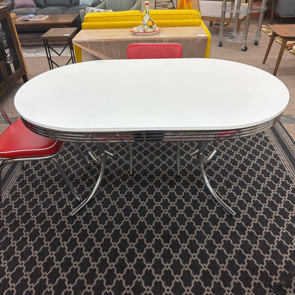 White oval table with chrome legs in a room with red chairs and patterned rug
