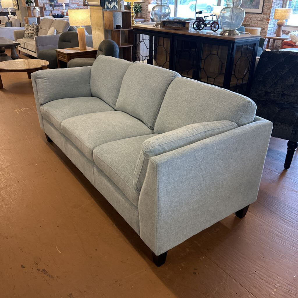 Gray sofa in a room with wooden flooring and furniture.