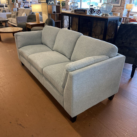 Gray sofa in a room with wooden flooring and furniture.