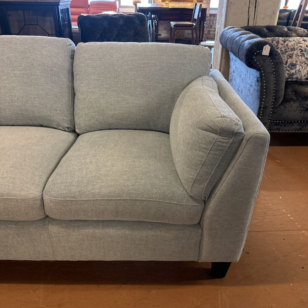 Gray sofa in a room with wooden flooring and furniture.