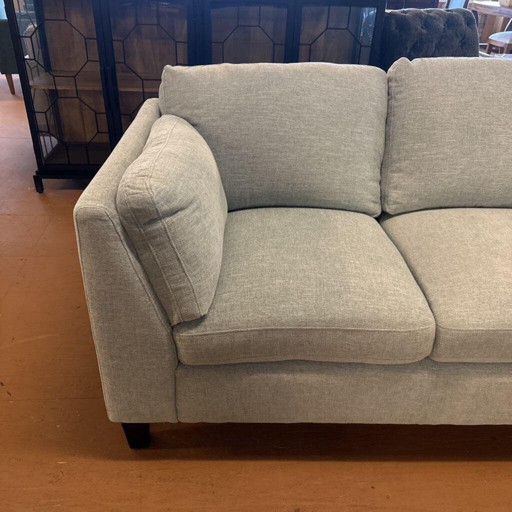 Beige sofa on a wooden floor with a decorative wall in the background