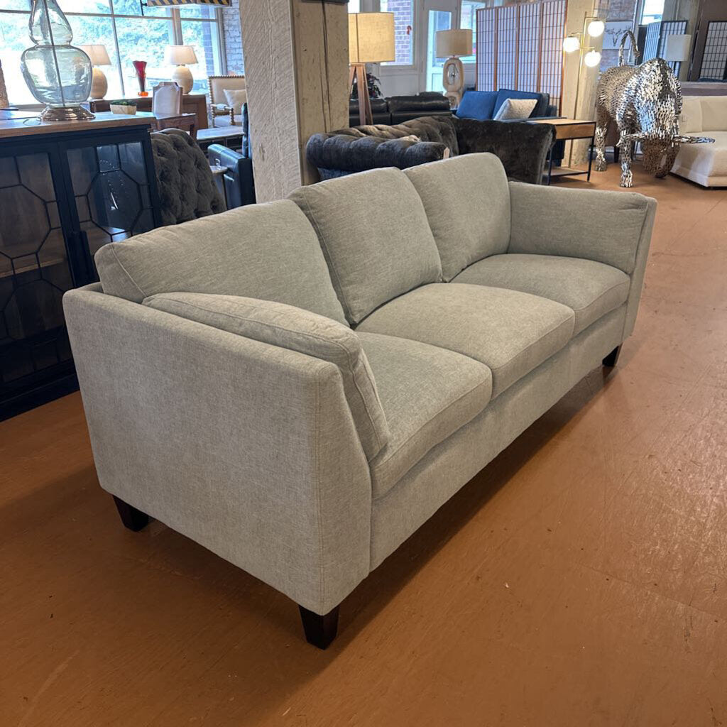Gray sofa in a showroom setting with other furniture and decor items.