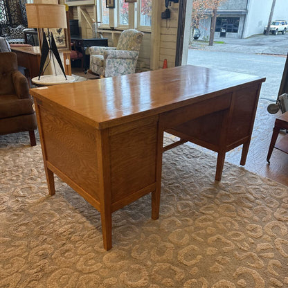 Wooden desk in a room with chairs and a lamp