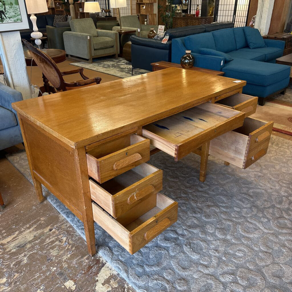 Wooden desk with multiple drawers in a room with furniture and decor.