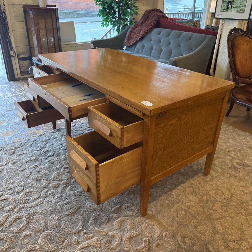 Wooden desk with drawers in a room with furniture and decor.