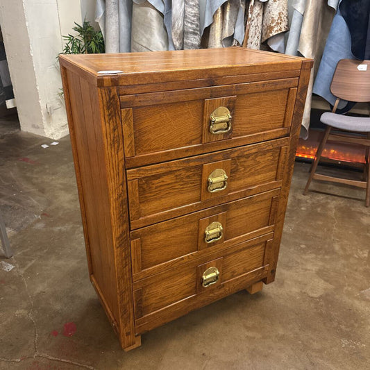 Wooden chest of drawers with brass handles in an indoor setting