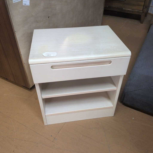 Small wooden nightstand with a drawer on a floor.