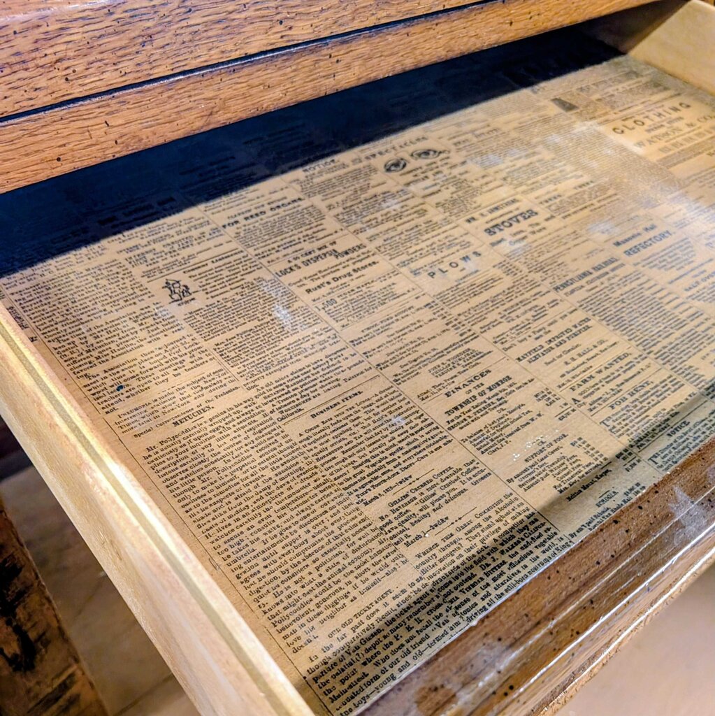 Wooden surface with a decorative paper pattern resembling text.