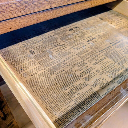 Wooden surface with a decorative paper pattern resembling text.