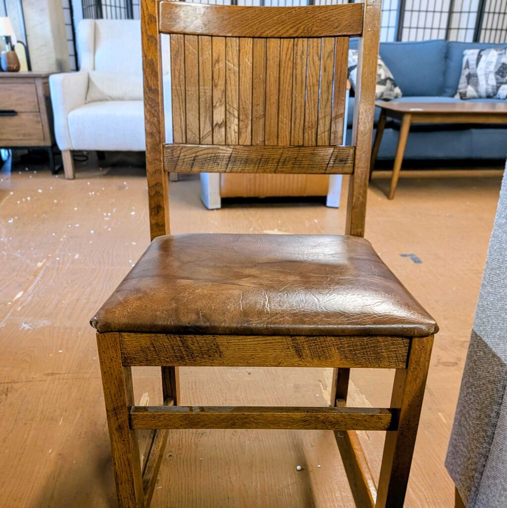 Wooden chair with a brown leather seat in an indoor setting