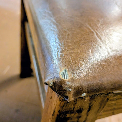 Close-up of a brown leather surface with visible wear and tear.