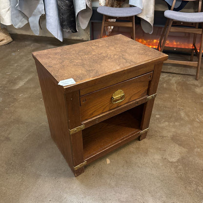 Wooden nightstand with a single drawer on a concrete floor