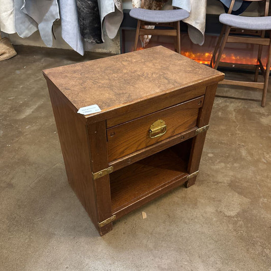 Wooden nightstand with a single drawer on a concrete floor