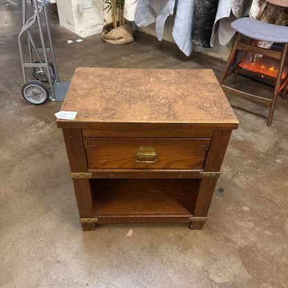 Wooden side table with a single drawer on a concrete floor.