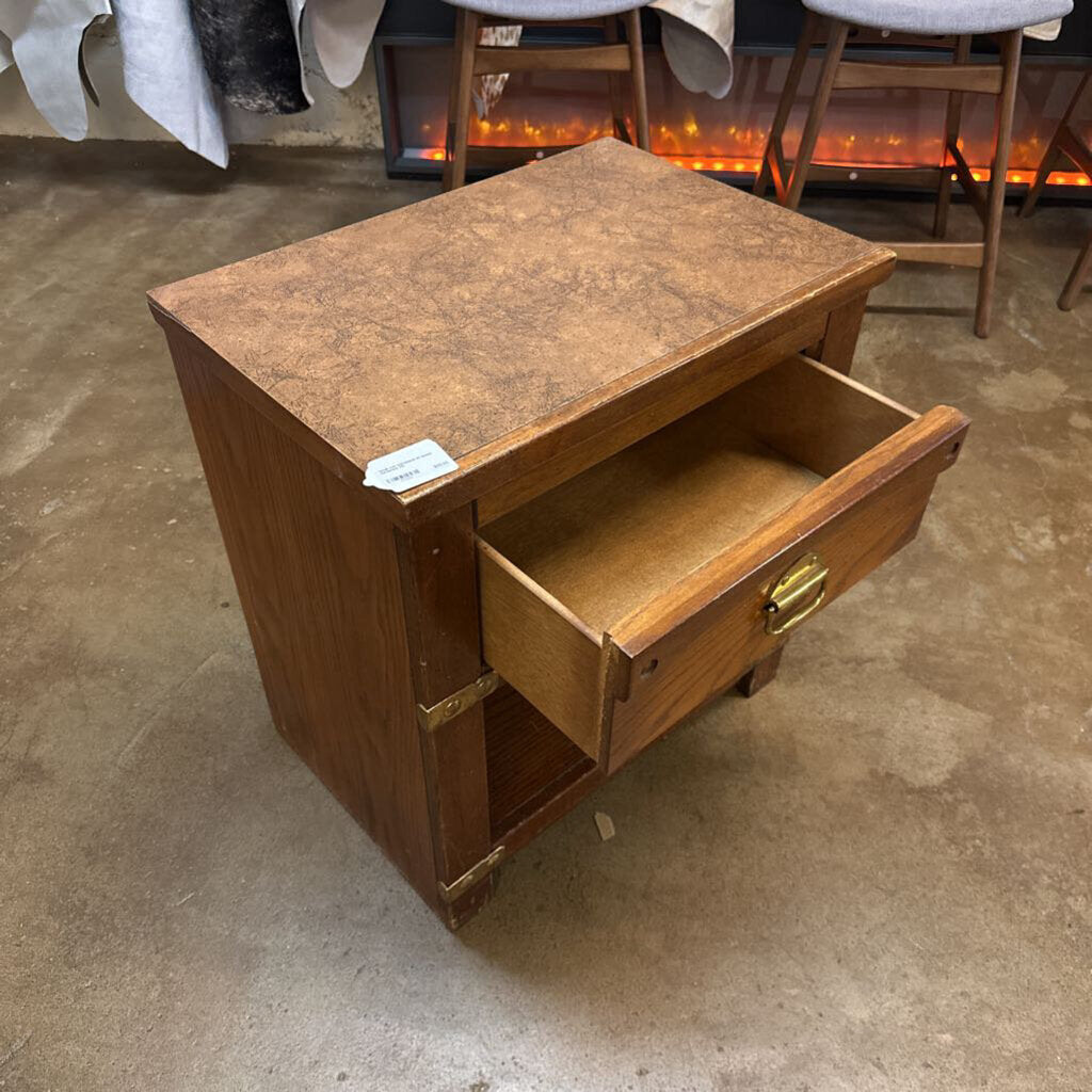 Wooden nightstand with a single drawer on a concrete floor