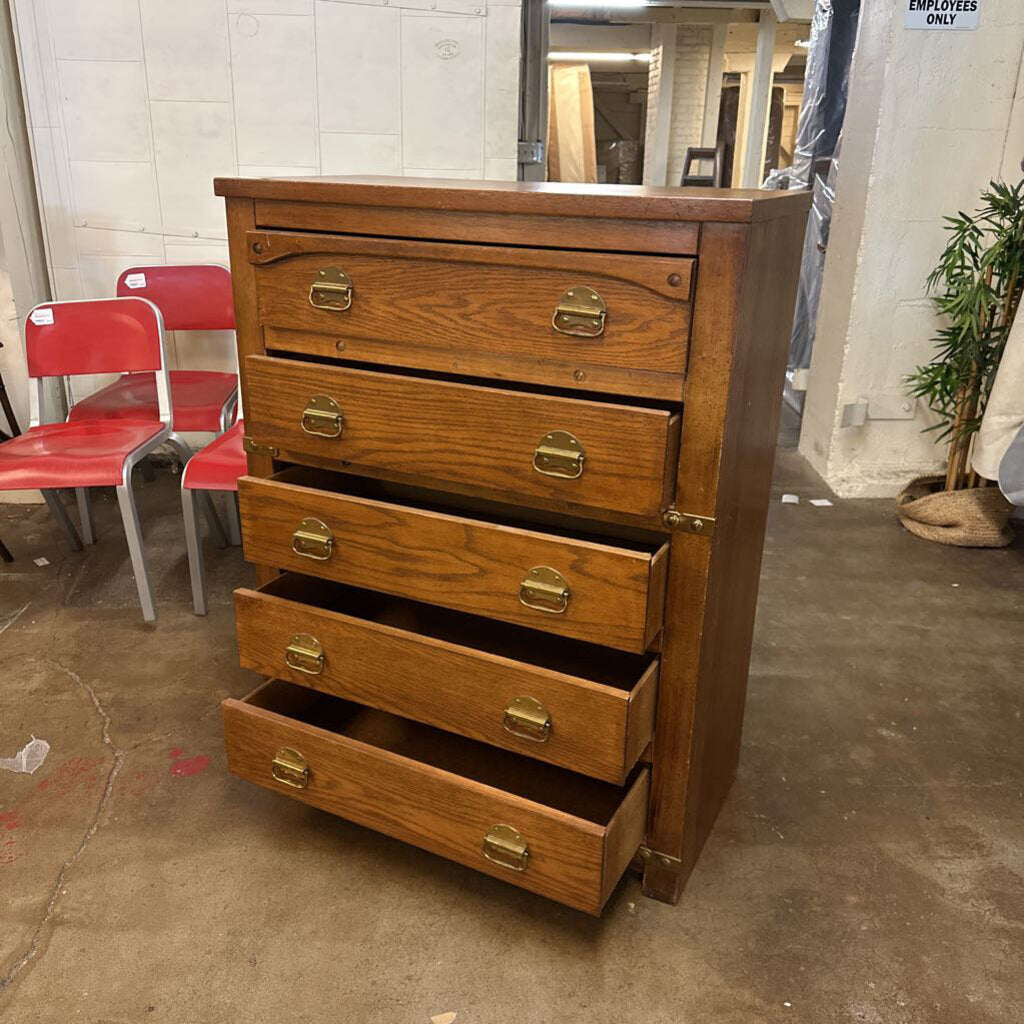 Wooden dresser with brass handles in a warehouse setting