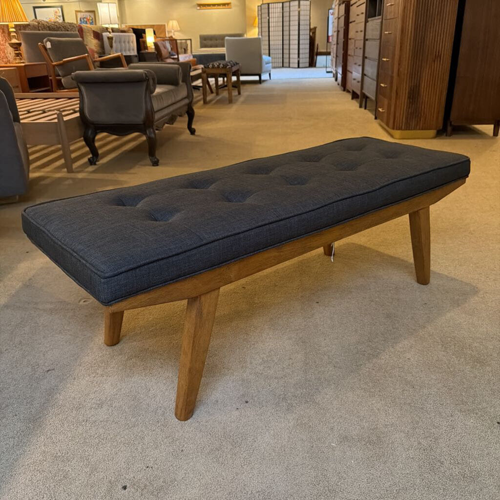 Wooden bench with dark cushion in a furniture store setting