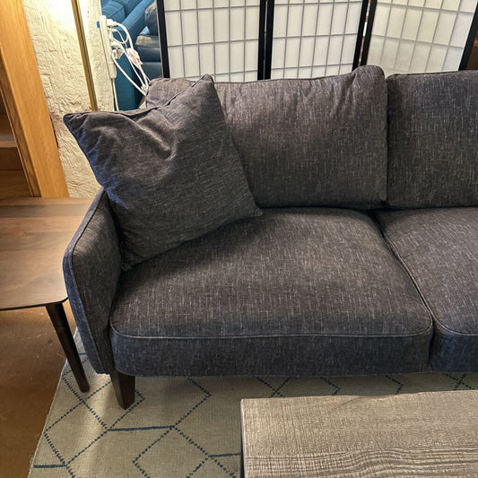 Gray sofa in a room with a wooden floor and a rug.