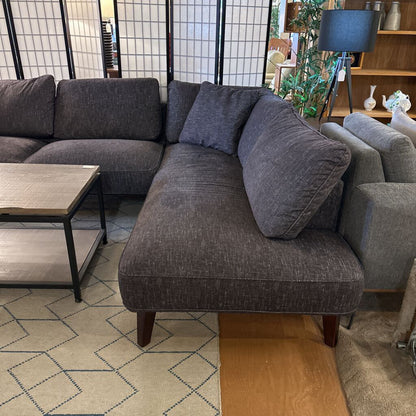 Gray sectional sofa with cushions in a living room setting.