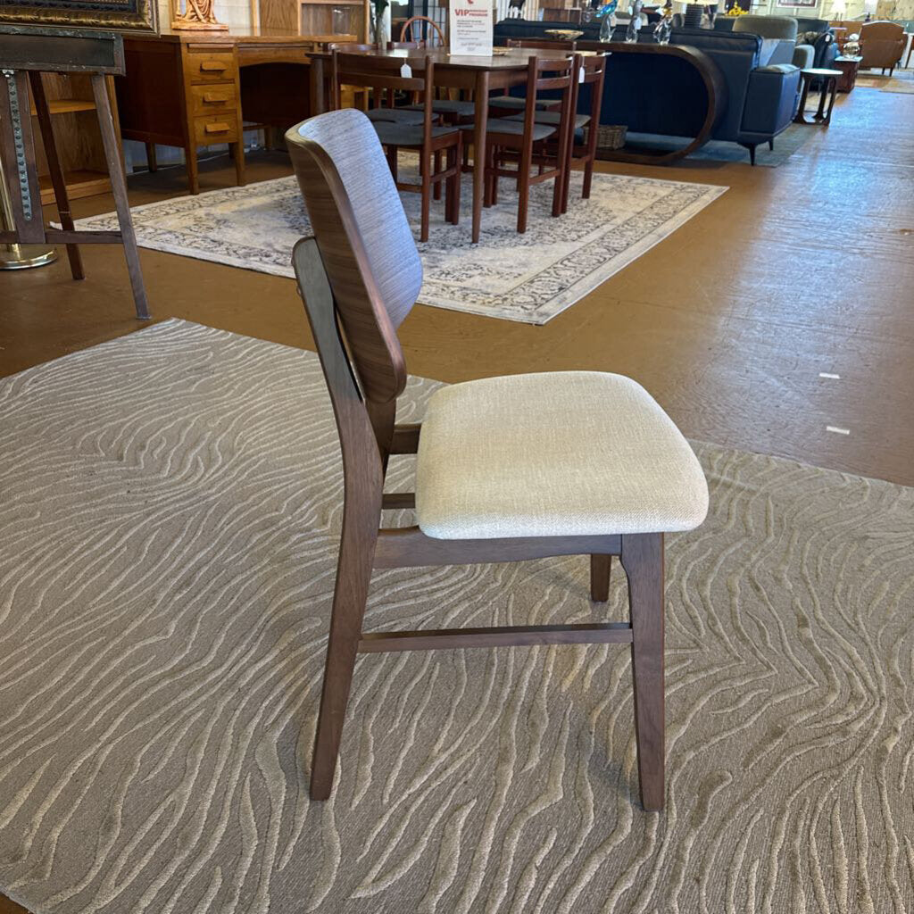 Chair with wooden frame and beige cushion on a patterned carpet in a furniture store.