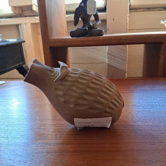 White ceramic piggy bank on a wooden surface with a blurred background