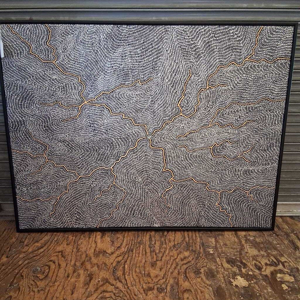 Framed abstract artwork with wavy lines on a wooden floor