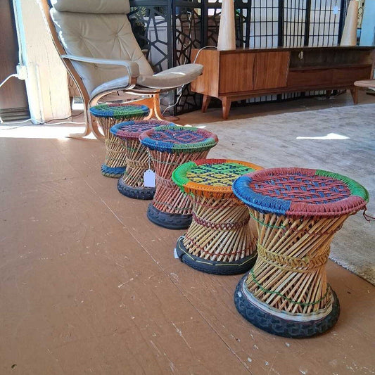 Colorful wicker stools arranged on a wooden floor with a chair and furniture in the background.