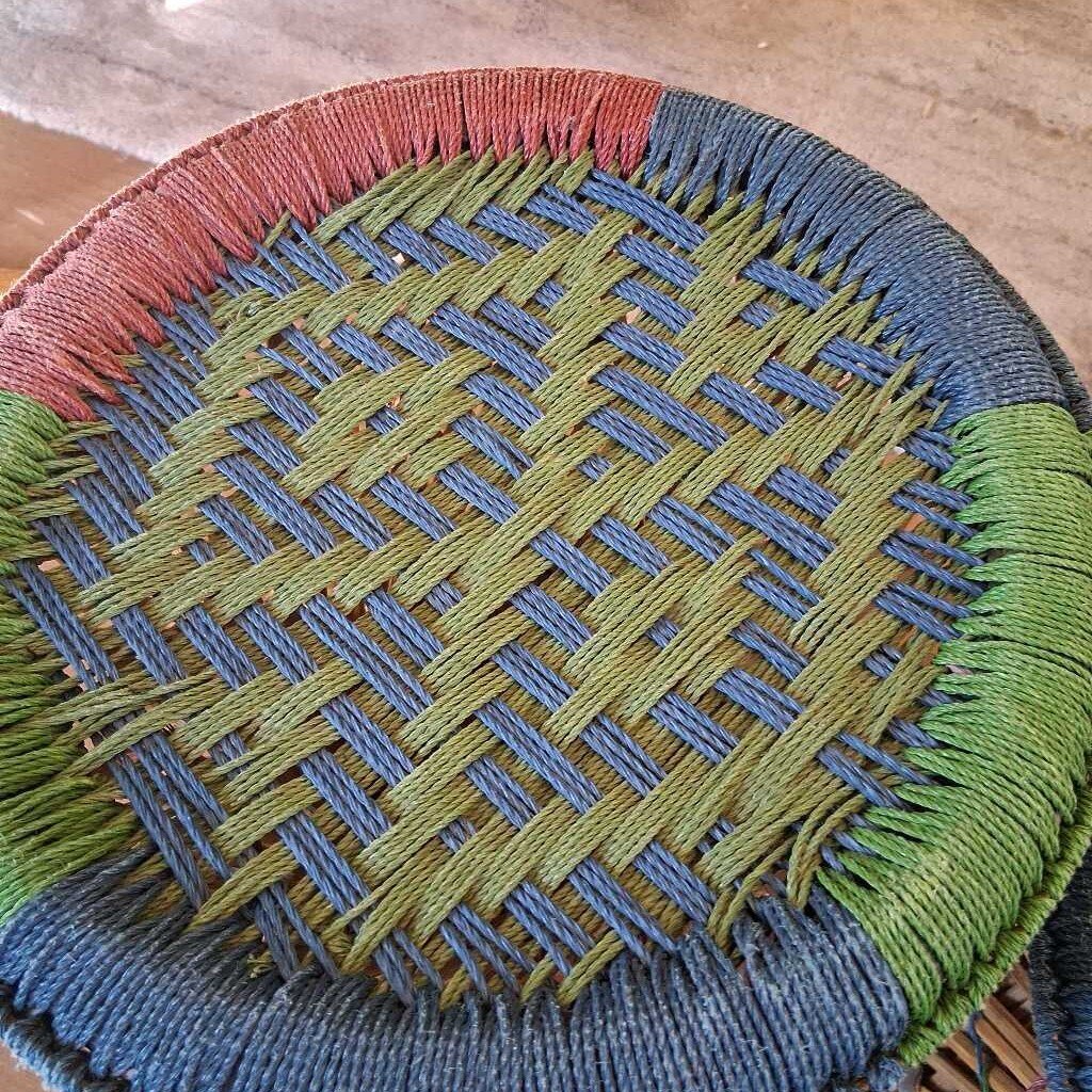 Woven mat with multicolored border on a wooden surface