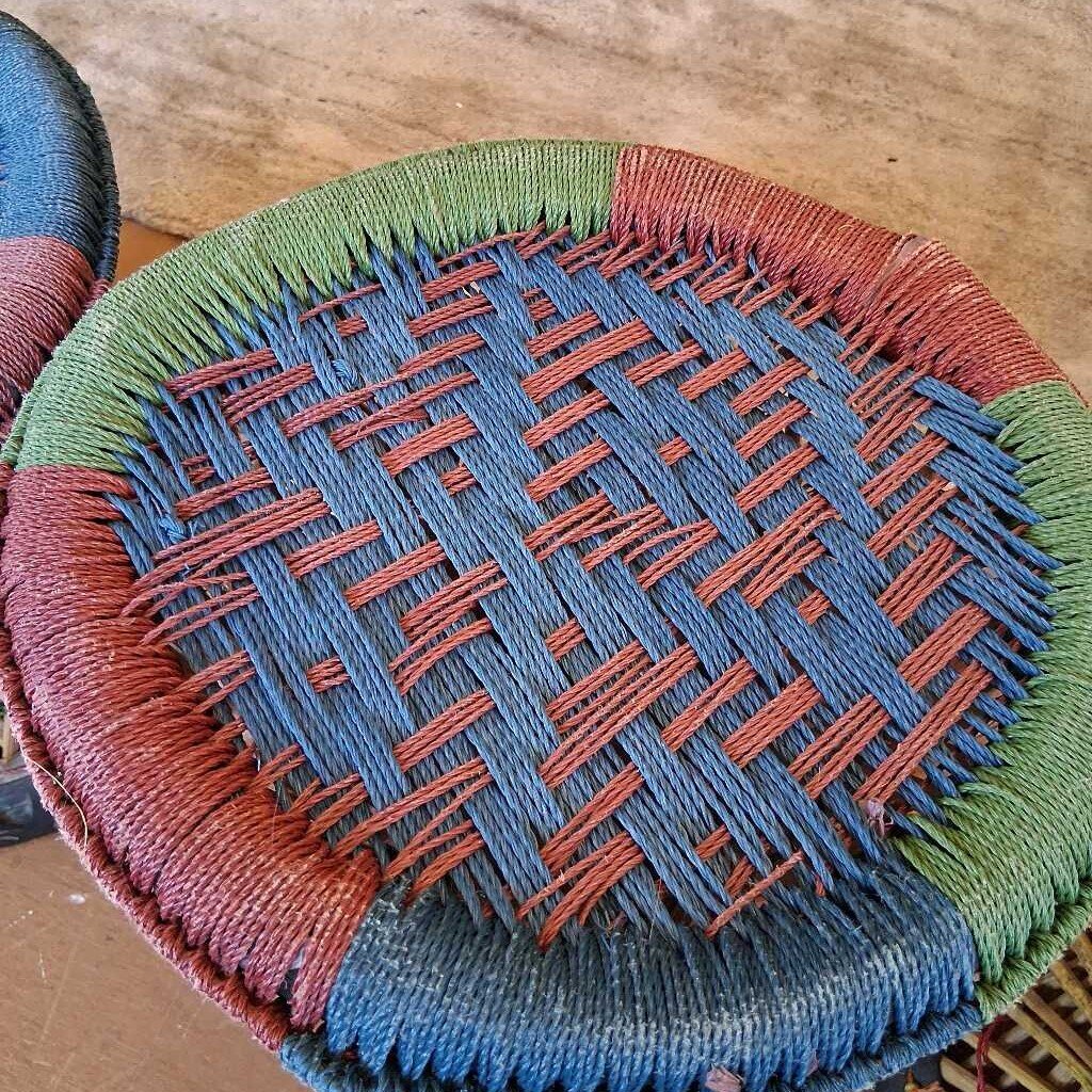 Close-up of a woven basket with red and blue patterns on a wooden surface