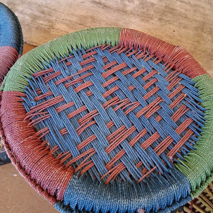 Close-up of a woven basket with red and blue patterns on a wooden surface