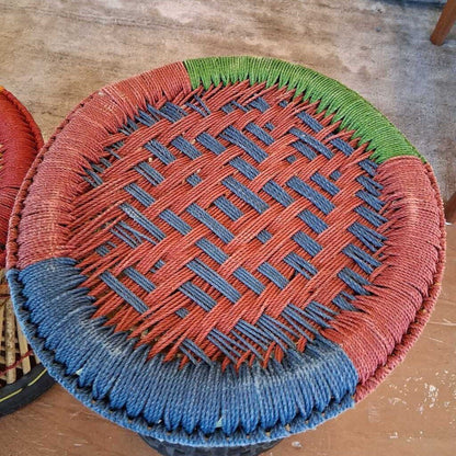 Woven basket with red, blue, and green pattern on a wooden surface