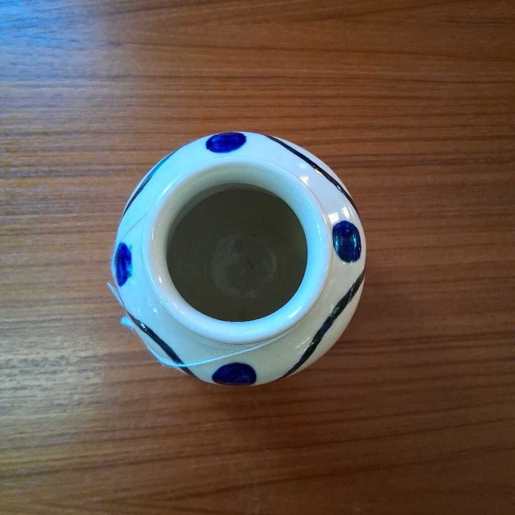 Small ceramic jar with blue polka dots on a wooden surface