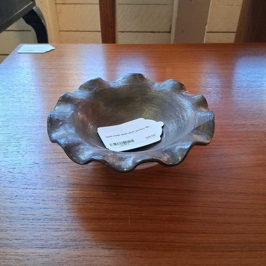 Decorative metal bowl on a wooden table with a visible tag.