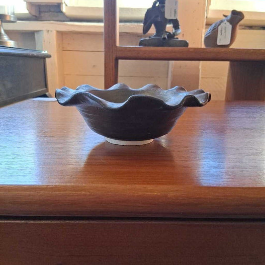 Decorative metal bowl on a wooden table with a visible tag.