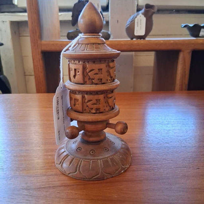 Wooden prayer wheel with carvings on a wooden table