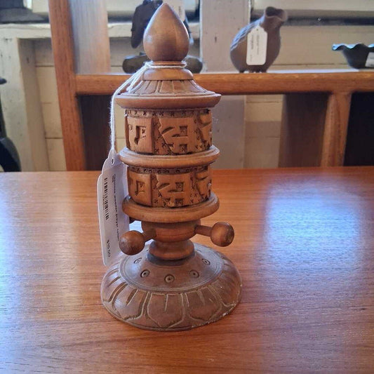Wooden prayer wheel with carvings on a wooden table