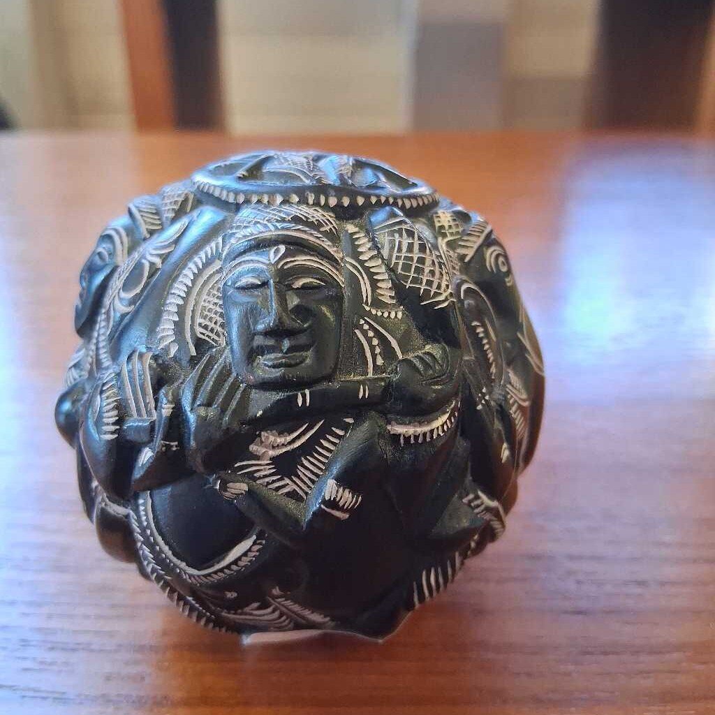 Decorative stone with intricate carvings on a wooden surface
