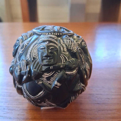 Decorative stone with intricate carvings on a wooden surface