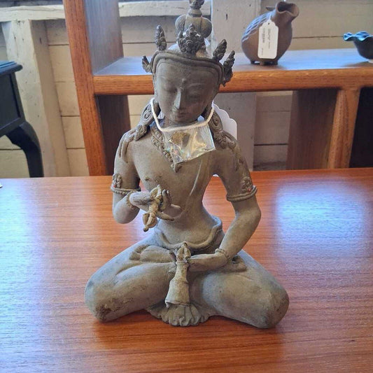 Statue of a seated figure on a wooden table with a blurred background