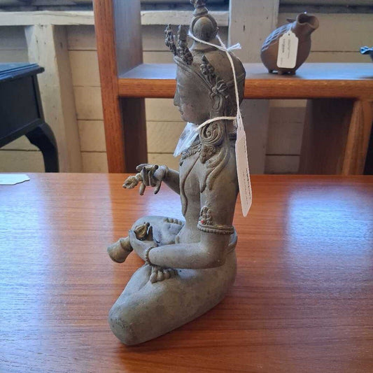 Statue of a seated figure on a wooden table with a blurred background