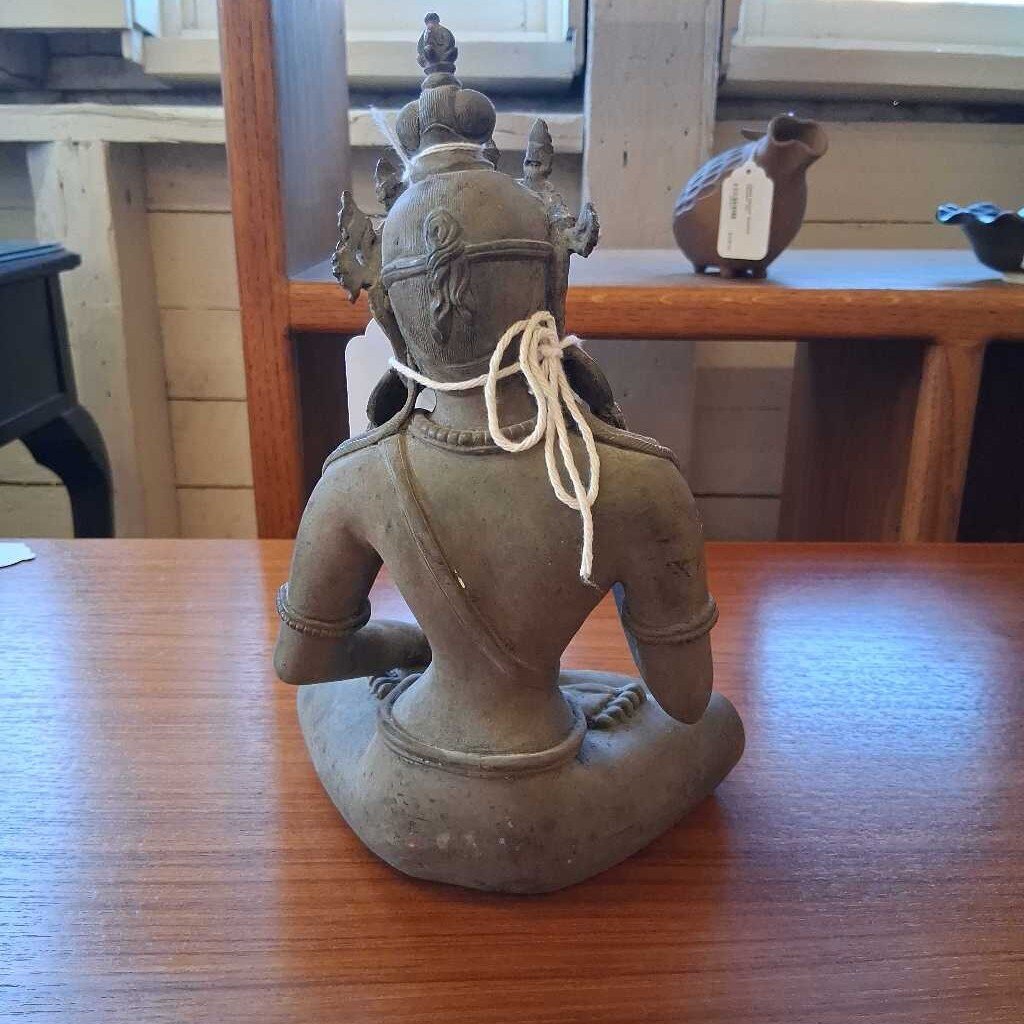 Statue of a seated figure on a wooden table with a blurred background