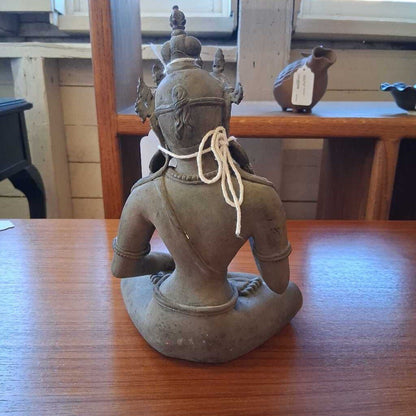 Statue of a seated figure on a wooden table with a blurred background