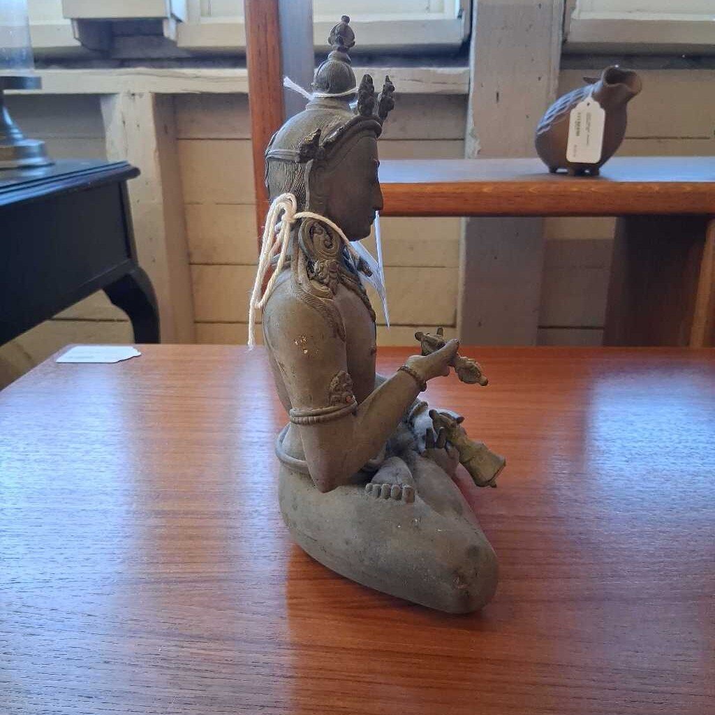 Statue of a seated figure on a wooden table with a blurred background