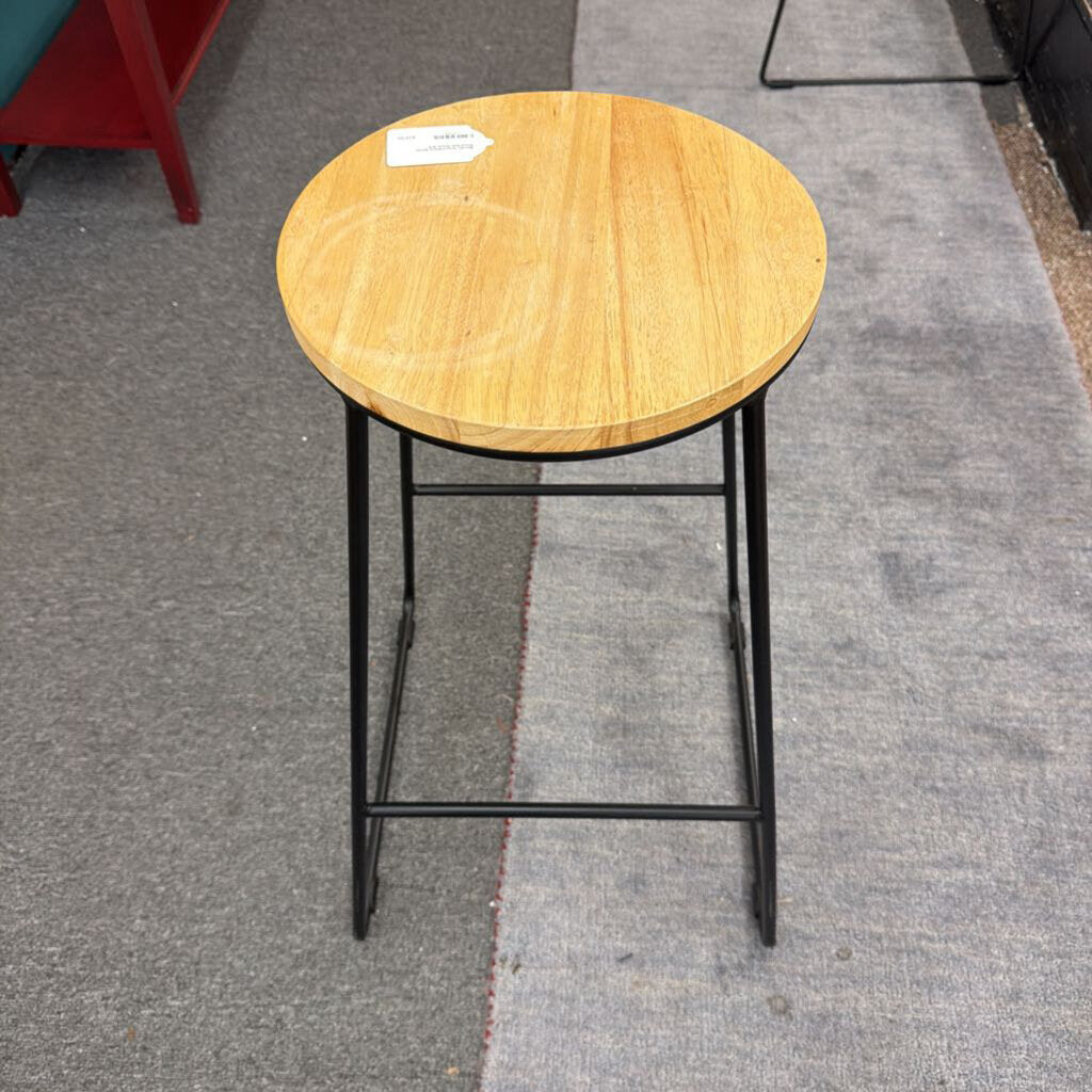 Wooden bar stool with black metal legs on a gray floor