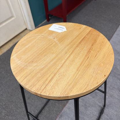 Round wooden table with a black metal frame on a gray floor.