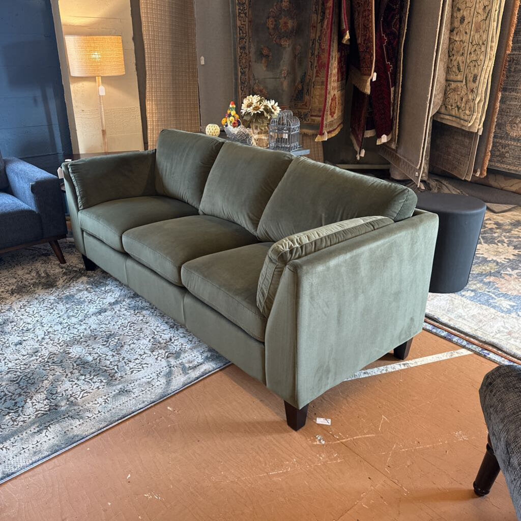 Green sofa in a room with rugs and a lamp