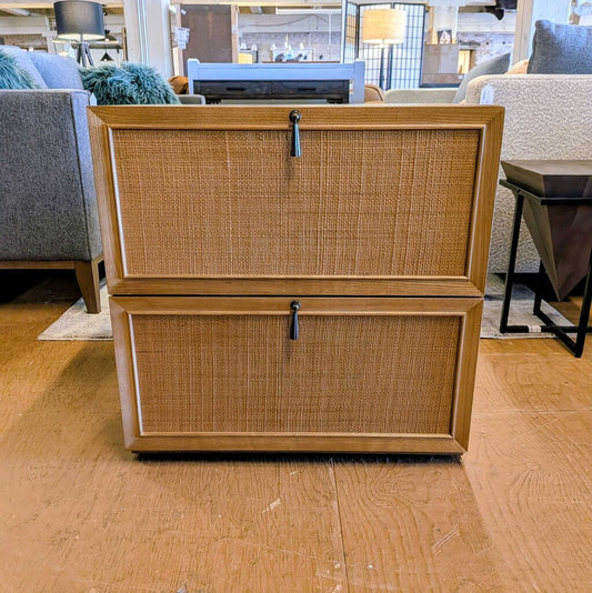 Wooden file cabinet with wicker-style doors in a room with furniture and decor.